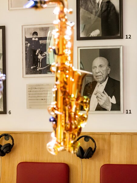 Saxophone and drum in front of historical musician photos.