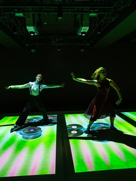 Dancing people on illuminated vinyl record projections.