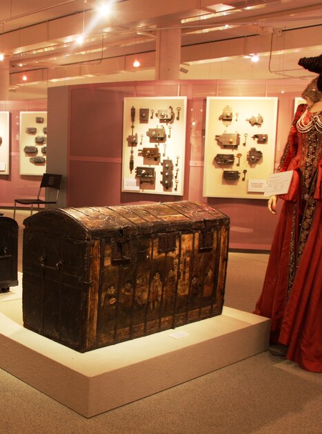 Historical chests and costumes in an exhibition. | © Schell Collection