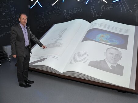 Eine Person zeigt auf ein großes, offenes Buch im Museum. | © UniGraz@Museum