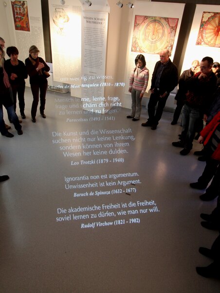 Besucher im Museum hören Zitate über Wissenschaft und Freiheit projiziert auf den Boden. | © UniGraz@Museum