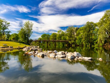 Reflective river in Augartenbucht in Graz under a blue sky.  | © Graz Tourismus - Harry Schiffer