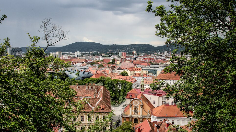 Panoramic view of Graz showcasing red rooftops and the Kunsthaus. | © Angelika Schwaff_Reisefreunde