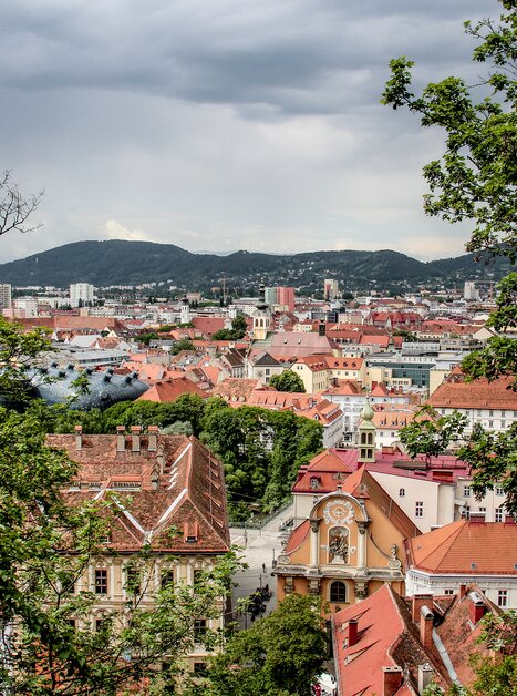 Panoramic view of Graz showcasing red rooftops and the Kunsthaus. | © Angelika Schwaff_Reisefreunde