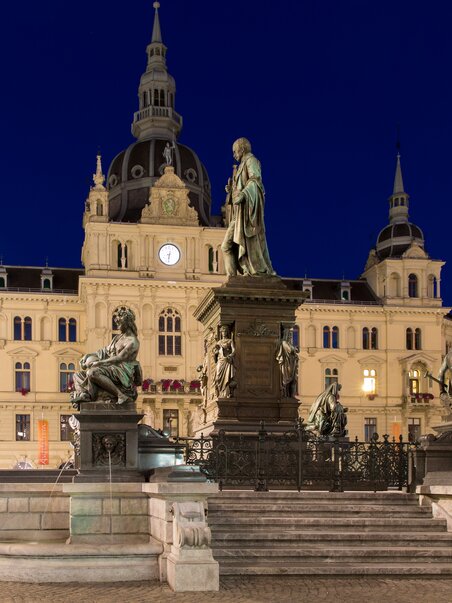Evening view of the Town Hall at Hauptplatz in Graz with statues and historical background. | © Graz Tourismus - Harry Schiffer