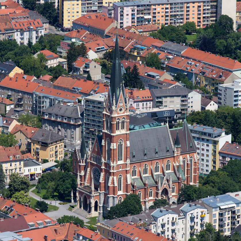 Herz-Jesu-Kirche a Graz | © Graz Tourismus - Harry Schiffer Vista sulla città di Graz con una chiesa prominente circondata da edifici residenziali. | © Graz Tourismus - Harry Schiffer