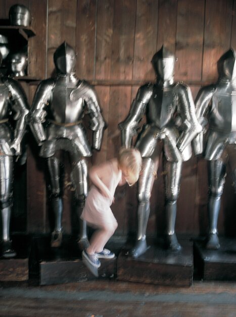 Ein Kind springt zwischen vier Ritterrüstungen im Landeszeughaus. | © Graz Tourismus - Elfi Semotan