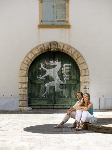 Paar im Landhaushof in Graz, vor einer alten Tür mit grünem Anstrich und dem steirischen Panther. | © Graz Tourismus - Tom Lamm