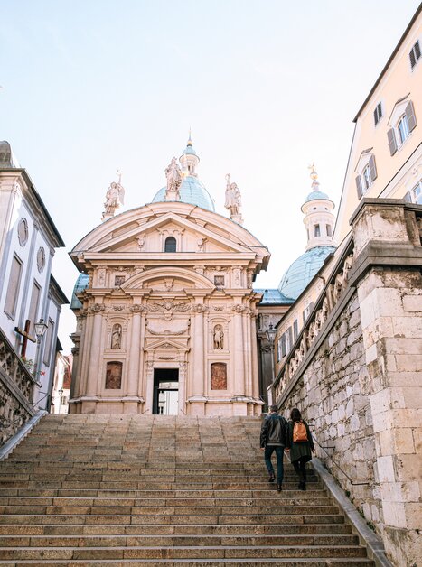 Zwei Personen gehen die Treppen zum Mausoleum neben dem Grazer Dom hinauf. | © Graz Tourismus