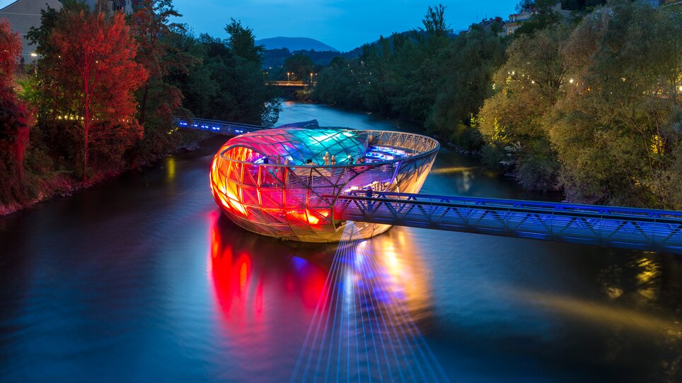 Die Murinsel in Graz leuchtet farbenfroh über der Mur. | © Graz Tourismus - Harry Schiffer