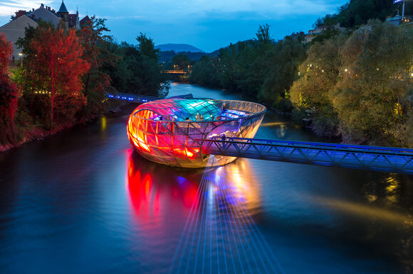 The Island in the Mur in Graz shines colorfully over the Mur. | © Graz Tourismus - Harry Schiffer