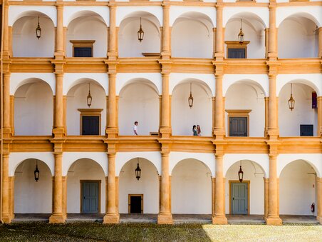 Inner courtyard of Eggenberg Palace with arches and people. | © Graz Tourismus - Mias Photoart