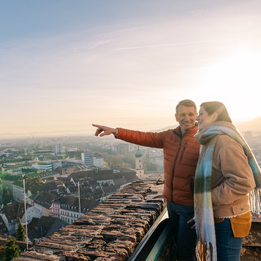 Paar genießt den Ausblick vom Schlossberg in Graz bei Sonnenuntergang. | © Graz Tourismus - Mias Photoart