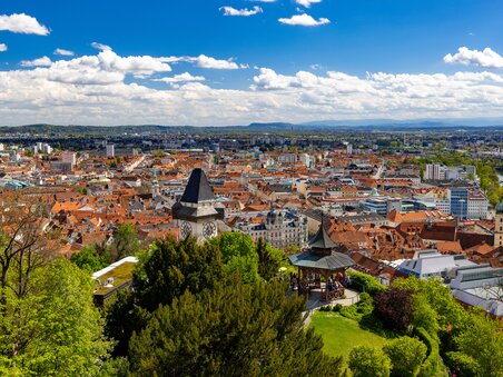 View over Graz featuring the clock tower on Schlossberg and the Mur. | © Graz Tourismus - Harry Schiffer