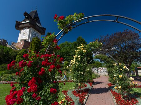 La torre dell'orologio sul Schlossberg a Graz, circondata da un giardino fiorito. | © Graz Tourismus - Harry Schiffer