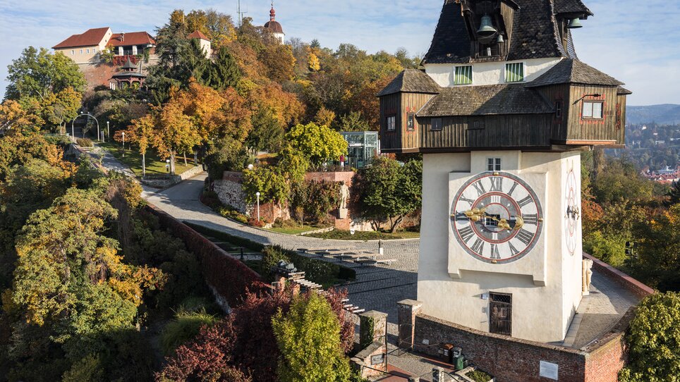 Der Uhrturm auf dem Schlossberg in Graz, umgeben von buntem Herbstlaub. | © Graz Tourismus - zepp-cam