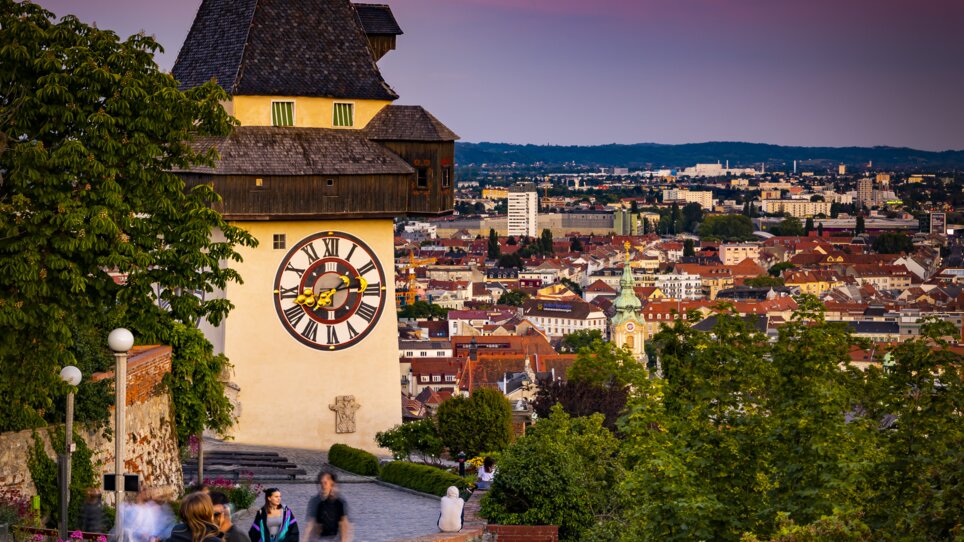 Der Uhrturm überblickt die Stadt Graz bei Sonnenuntergang. | © Graz Tourismus - Werner Krug
