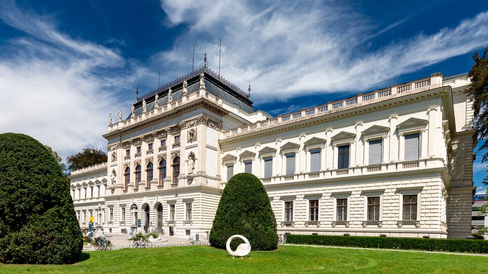 View of the Karl Franzens University of Graz with green lawn and blue sky.
 | © Graz Tourismus - Harry Schiffer