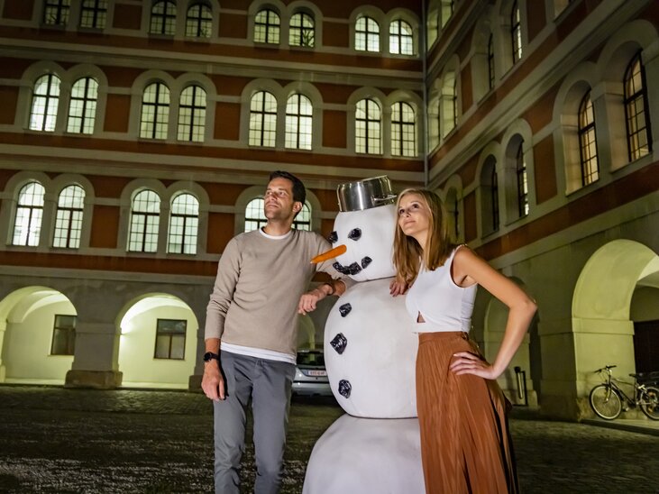 Paar mit einem Schneemann im Innenhof des Priesterseminars bei einem geführten Abend-Rundgang in Graz. | © Graz Tourismus - Werner Krug