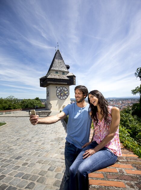 Paar macht ein Selfie mit dem Uhrturm in Graz im Hintergrund. | © Graz Tourismus - Tom Lamm