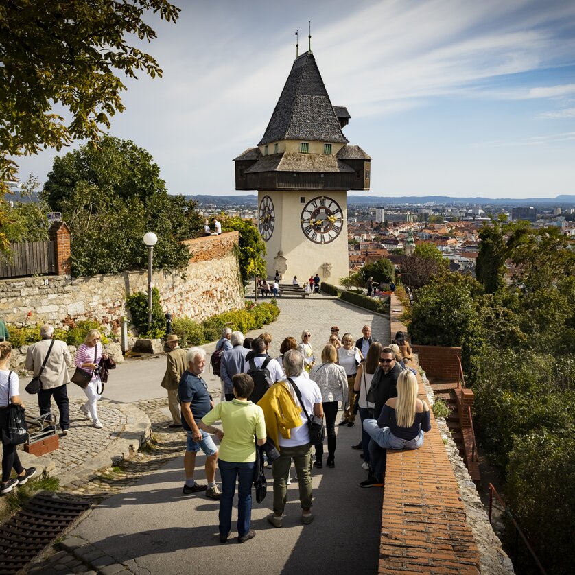 Besucher erkunden den Schlossberg mit Blick auf den Grazer Uhrturm und die Stadt Graz. | © Graz Tourismus - Werner Krug