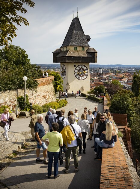 Besucher erkunden den Schlossberg mit Blick auf den Grazer Uhrturm und die Stadt Graz. | © Graz Tourismus - Werner Krug