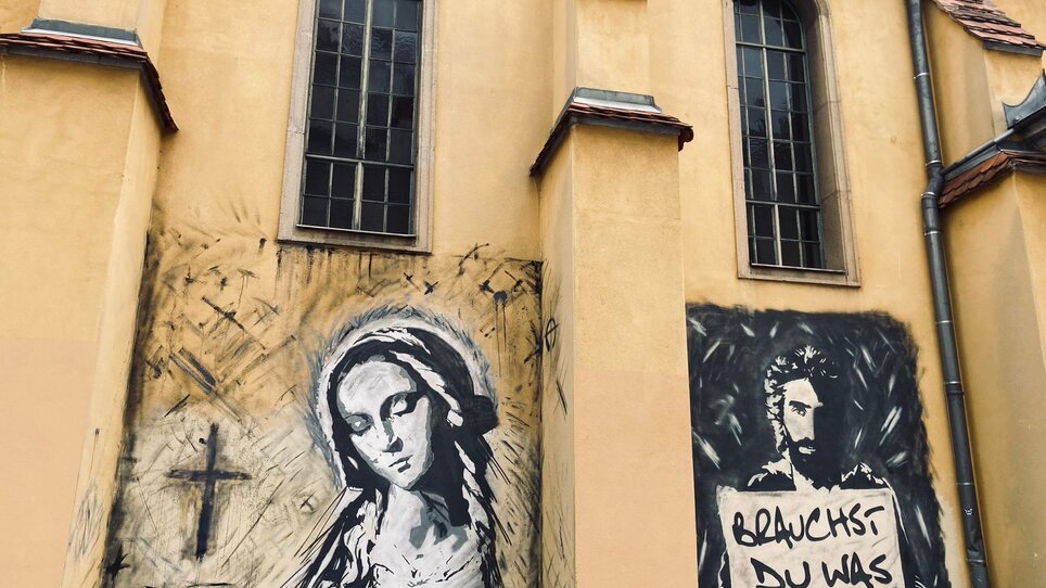 Kunstwerke an einer Kirche zeigen Maria und Jesus mit Spruch. | © Graz Tourismus - Nadja Albrecht