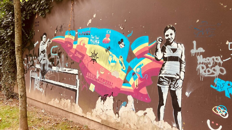 Graffiti mit bunten Mustern und Figuren an einer Wand in Graz. | © Graz Tourismus - Nadja Albrecht