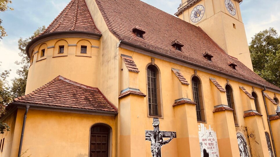 Bunte Kirche mit großem Kreuz und Wandkunst in Graz. | © Graz Tourismus - Nadja Albrecht