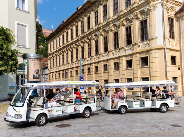 Ein Elektroshuttle auf einer Stadttour in Graz, mit Passagieren. | © Graz Tourismus - Harry Schiffer