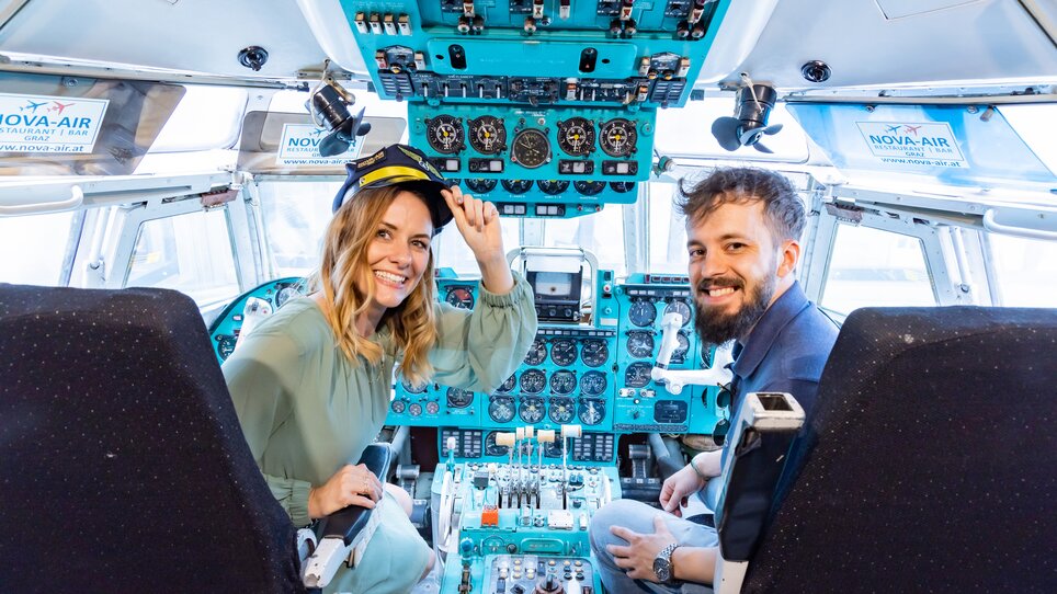 Two people in the cockpit of an aeroplane at the Novapark Flugzeughotel Graz. | © Graz Tourismus - Werner Krug