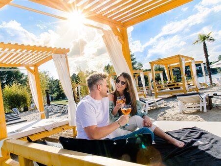 Ein Paar genießt Cocktails in einer Strandlounge mit Sonnenschein. | © Region Graz - Mias Photoart