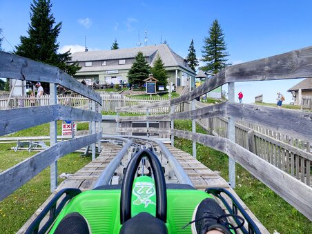 Blick auf die Sommerrodelbahn, die zu einem Gebäude führt. | © achtzigzehn - Hinterleitner