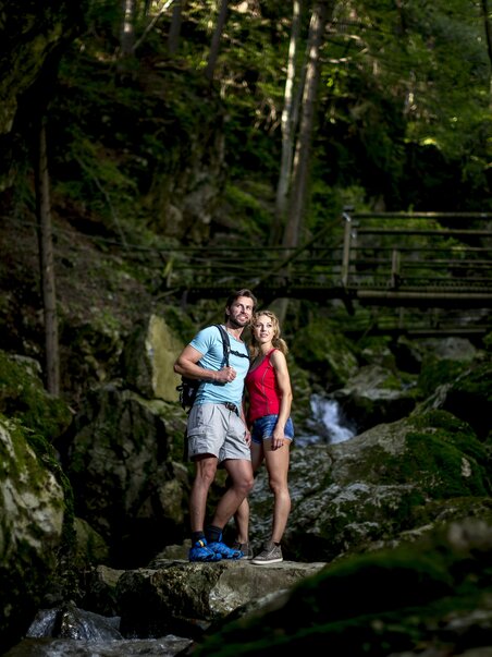 Paar posiert in der Kesselfallklamm umgeben von Wald und Felsen. | © Region Graz - Tom Lamm