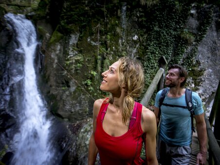 Ein Paar bewundert den Kesselfallklamm Wasserfall während einer Wanderung. | © Region Graz - Tom Lamm