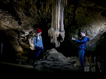 Zwei Personen erkunden die Lurgrotte Peggau, fotografieren Stalaktiten. | © Region Graz - Tom Lamm