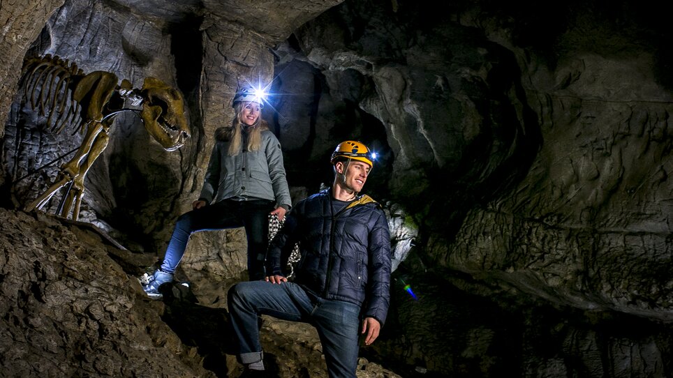 Zwei Personen in der Lurgrotte Peggau neben einem Dinosaurierskelett. | © Region Graz - Tom Lamm