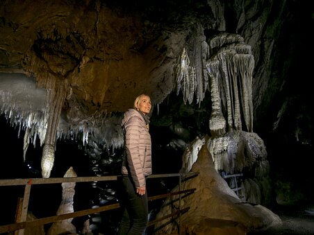 Frau steht in der Lurgrotte Semriach und bewundert beeindruckende Stalaktiten. | © Region Graz - Tom Lamm