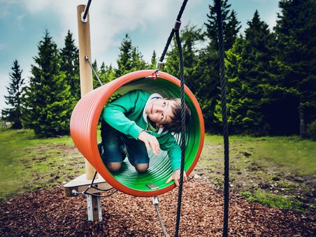 A boy is playing in colorful playground equipment outdoors. | © Lupi Spuma