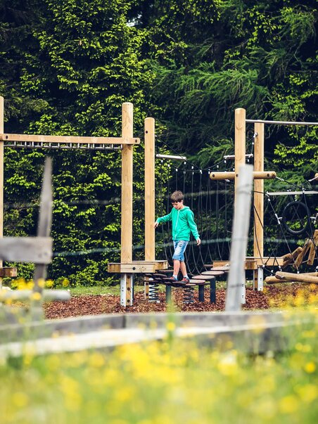 A boy plays on a climbing structure in a playground setting. | © Lupi Spuma