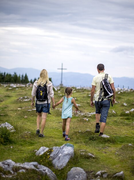 Familie wandert Hand in Hand über eine Wiese am Schöckl. | © Region Graz - Tom Lamm