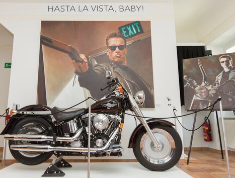 A motorcycle in front of a mural featuring the phrase "Hasta la Vista, Baby!". | © Region Graz - Harry Schiffer