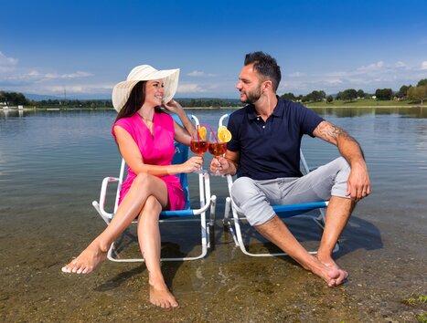 Coppia che si rilassa allo Schwarzlsee con cocktail in mano. | © Region Graz - Harry Schiffer