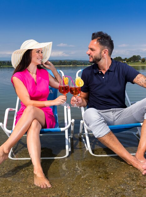 Couple relaxing at Schwarzlsee with cocktails in hand. | © Region Graz - Harry Schiffer