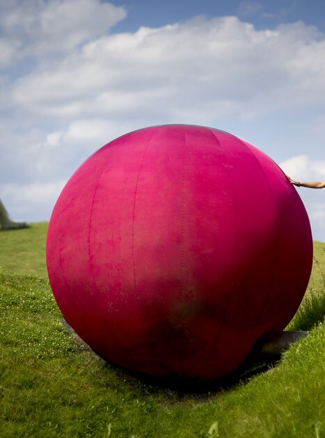 Eine Frau mit einer großen pinken Kugel im Österreichischen Skulpturenpark. | © Region Graz - Tom Lamm