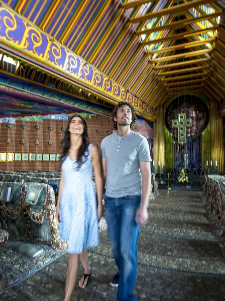 Ein Paar geht durch eine lebhaft dekorierte Kirche. | © Region Graz - Tom Lamm