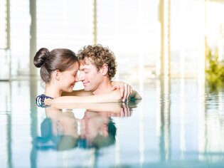Ein Paar genießt einen romantischen Moment im Wasser der Therme Nova. | © Lipizzanerheimat-Die Abbilderei