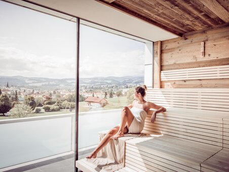Frau sitzt in der Therme Nova  in der Sauna und mit Blick in die Landschaft | © Lipizzanerheimat-Die Abbilderei