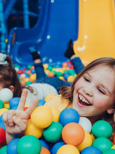 Two kids are playing in a ball pit, smiling. | © Lex Karelly