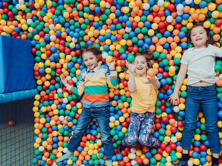 Three happy kids lying in a colorful ball pit. | © Lex Karelly